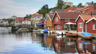 Bunte Holzhäuser spiegeln sich im Wasser der norwegischen Küste.