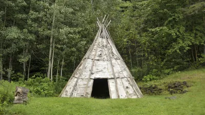 Traditionelles Tipi steht auf einer grünen Wiese vor einem Wald.