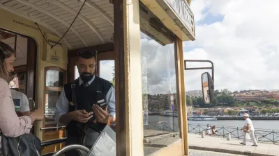 Mann mit Smartphone fährt in der Straßenbahn am Douro-Fluss entlang
