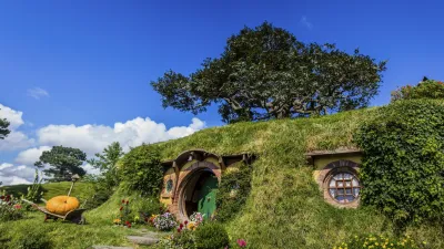 Gemütliches Hobbit-Loch mit blühendem Garten und grüner Vegetation.