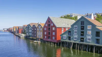 Bunte Holzhäuser stehen am Ufer eines Fjords in Norwegen.