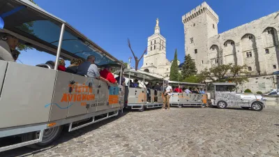 Touristen fahren mit einem Zug durch die mittelalterliche Stadt Avignon.