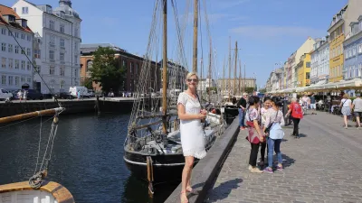 Frau steht an einem Kanal mit Segelbooten in Kopenhagen.