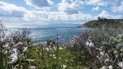 Leuchtturm und blühende Vegetation am Meer auf Sardinien.