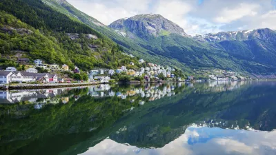 Norwegische Häuser spiegeln sich im ruhigen Fjordwasser.