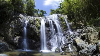 Kaskadierende Wasserfälle fließen über Felsen in einem tropischen Wald.