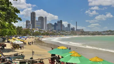 Strandlandschaft mit bunten Sonnenschirmen und Stadt im Hintergrund
