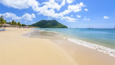 Karibischer Strand mit goldenem Sand und türkisfarbenem Wasser.