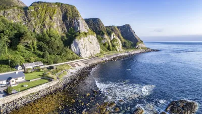 Küstenlandschaft mit Felsen, Wellen und Häusern an der irischen Küste.