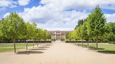 Historische Abtei Cluny mit gepflegtem Rasen und Baumallee