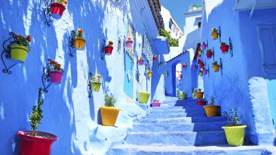 Blaue Häuser und Stufen mit bunten Blumentöpfen in Chefchaouen, Marokko.