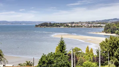 Strandlandschaft mit Küstenlinie und Vegetation im Vordergrund