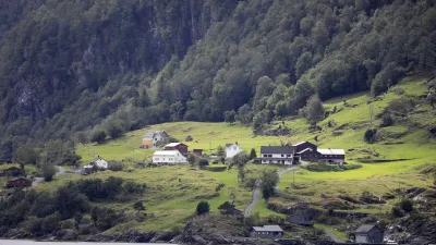 Norwegische Bauernhäuser liegen an einem Hang am Fjord.