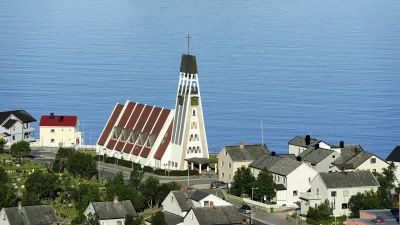 Weiße Kirche mit rotem Dach und hohem Turm am Ufer