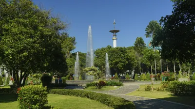 Ein Park mit einem Brunnen und einem hohen Turm im Hintergrund.
