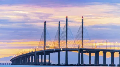 Die lange Brücke erstreckt sich über das türkisfarbene Meer bei Sonnenuntergang.