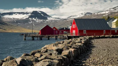 Rote Häuser stehen an der Küste Islands mit Blick auf das Meer.