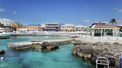 Türkisblaues Wasser umspült einen Bootsanleger mit bunten Häusern im Hintergrund.