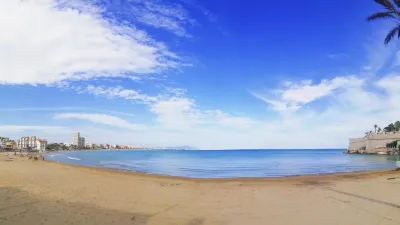 Sonnenverwöhntes Strandpanorama mit Burg und Palmen in Peniscola.