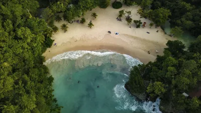 Türkisblaues Wasser trifft auf einen goldenen Sandstrand mit üppiger Vegetation.