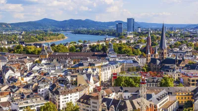 Bonn zeigt eine Luftaufnahme der Stadt am Rhein mit Gebäuden und Grünflächen.