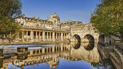Historische Brücke mit Säulen über ruhigem Wasser in Bath