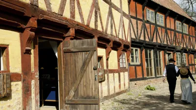 Zwei Personen gehen an historischen Fachwerkhäusern vorbei