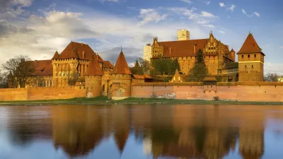 Das mittelalterliche Schloss Marienburg spiegelt sich im Wasser.
