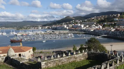 Blick auf den Hafen von Baiona mit vielen Segelbooten und der historischen Stadtmauer.