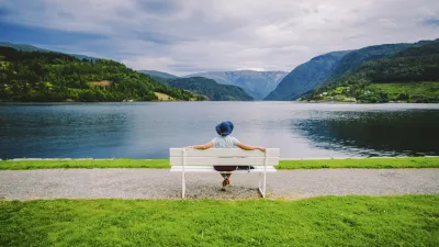 Frau sitzt auf einer Bank und blickt auf den Fjord.