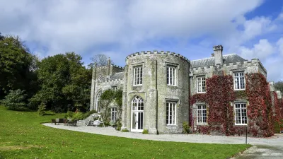 Historisches Herrenhaus mit Efeu bewachsen auf einer grünen Wiese.