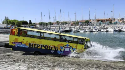 Ein gelber Hippotrip-Bus fährt ins Wasser und spritzt dabei hoch.