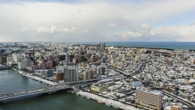 Schneebedeckte Stadtlandschaft mit Fluss und Bergen im Hintergrund