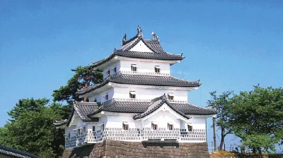 Weißes japanisches Schloss steht auf einem steinernen Fundament.