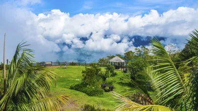 Grüner Rasen mit einem Pavillon und Blick auf bewölkte Berge.