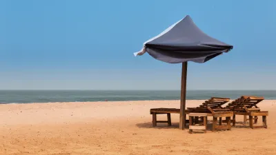 Strandliegen unter einem Sonnenschirm am sandigen Strand.