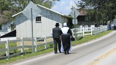 Amische Pärchen geht auf einer Landstraße entlang.