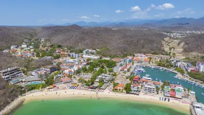 Blick auf eine Küstenstadt mit Strand und Yachthafen.