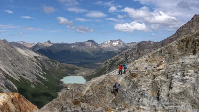 Wanderer erklimmen einen felsigen Berg mit Blick auf einen See.