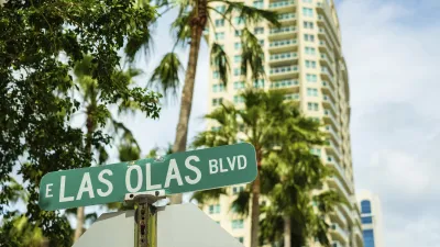 Straßenschild "Las Olas Boulevard" vor Palmen und Hochhäusern.