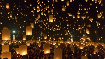 Menschen lassen leuchtende Laternen bei einem nächtlichen Fest in den Himmel steigen.