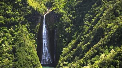 Wunderschöner Wasserfall stürzt zwischen üppiger grüner Vegetation hinab.