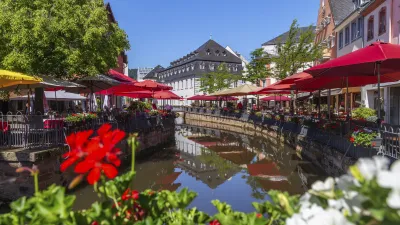 Bunte Häuser und Cafés säumen den Fluss in der Altstadt von Saarburg.