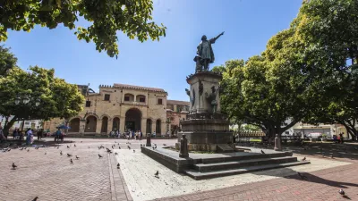 Ein Denkmal steht auf einem Platz vor einem historischen Gebäude.
