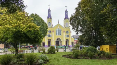 Helle Kirche mit zwei Türmen steht auf einem grünen Platz.