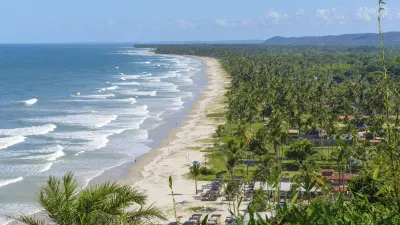 Weitläufiger Strand mit Palmen und Wellen am brasilianischen Küstenort Ilhéus.