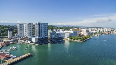 Hafen von Kota Kinabalu mit modernen Gebäuden und Booten im türkisfarbenen Wasser.