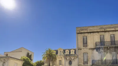 Historisches Gebäude mit Fassade und Palmen in Nimes, Frankreich
