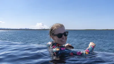 Eine lächelnde Frau entspannt im geothermalen Wasser.