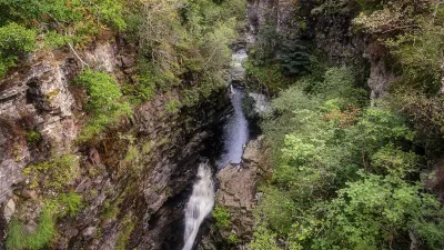 Wasserfall stürzt durch eine grüne Schlucht in Schottland.